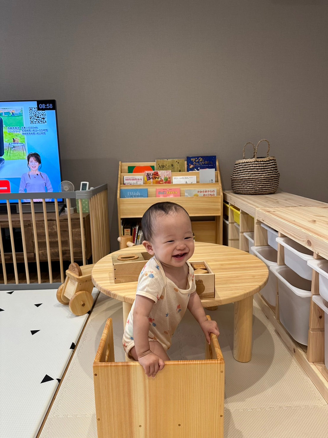 木のおもちゃと家具に囲まれて遊ぶ子ども