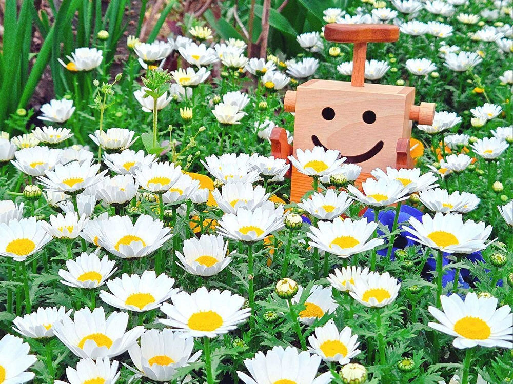 春のお花に囲まれたなかよしライブラリーのロボットクン