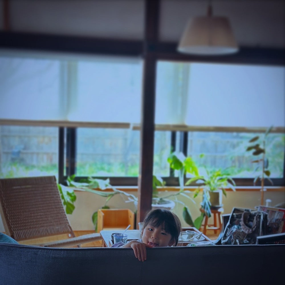 ソファの背もたれから顔をのぞかせる娘