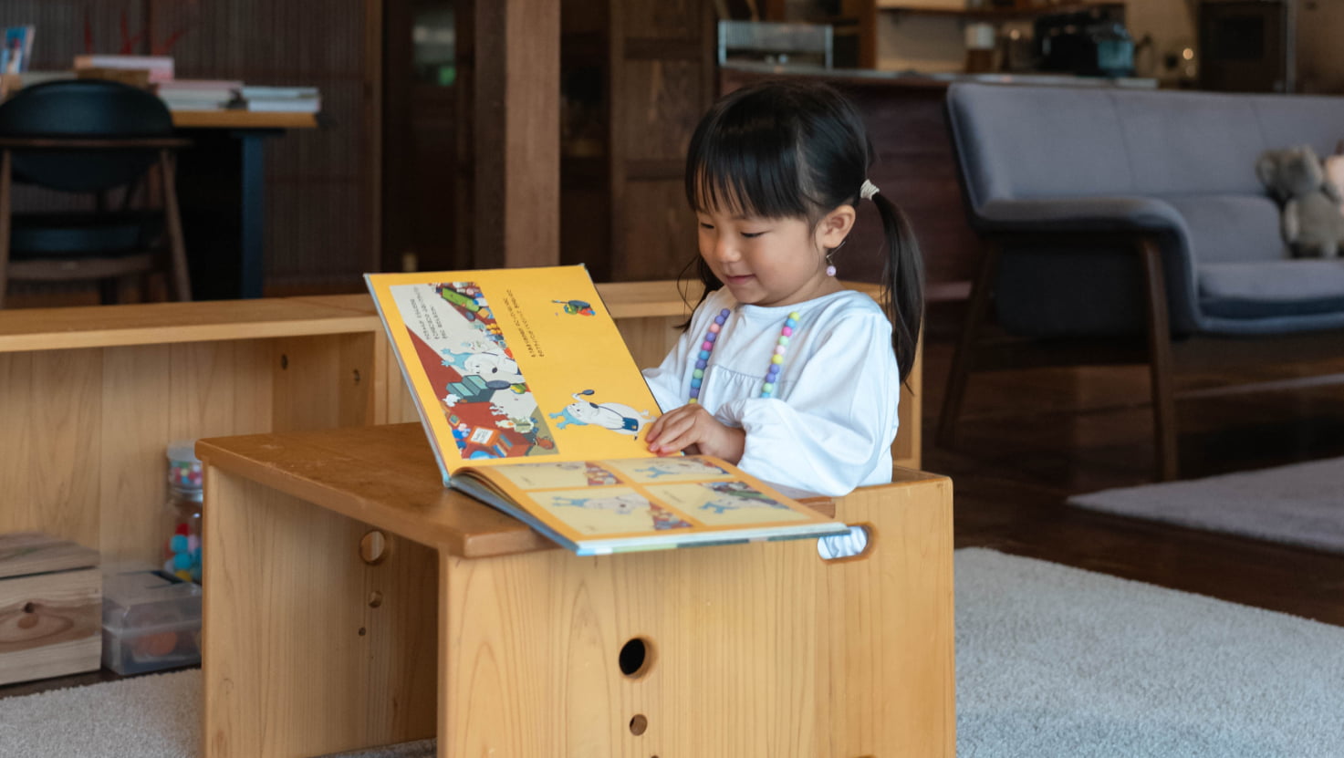 木製家具 子ども椅子とテーブルを使用して絵本を読んでいる様子